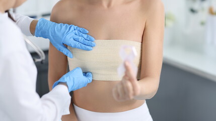 Doctor mammologist examining breast of female patient with elastic bandage closeup. Breast cancer prevention pink ribbon concept