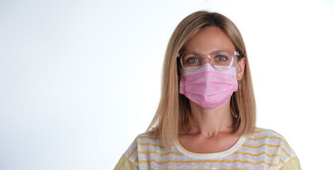 Portrait of young beautiful woman in pink protective medical mask and glasses. Mandatory mask mode...