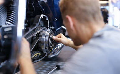 Mechanic repairs motorcycle engine in workshop. Motorcycle warranty service concept
