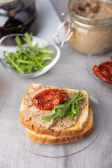 Chicken liver pate with wheat bread, arugula, sun-dried tomatoes and black tea. Homemade traditional rustic cuisine. Breakfast or snack option. Selective focus, close-up.
