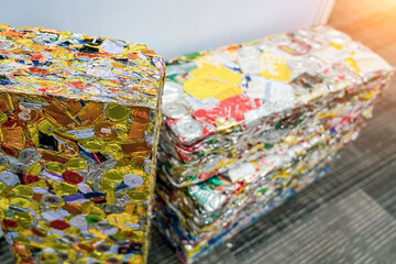 Aluminum cans pressed into large and heavy bales. Recycling and cleaning the environment from household waste. Garbage metal formed blocks from metal drink caps