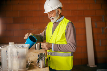 A senior site manager is preparing coffee at construction site.