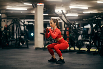 A female athlete is doing squats endurance at the gym.