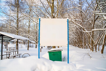 Template with blank sign. Public, summer picnic areas covered with snow. Barbecue grills in winter park.