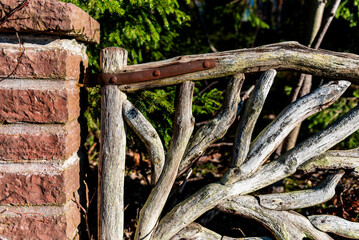 fragment of nice closed wooden garden gate. door made of tree branches