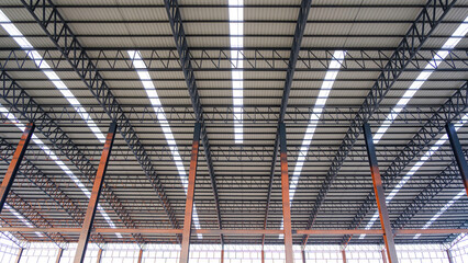 Curve metal roof beam structure with aluminium corrugated steel roof and skylights inside of large industrial factory building, Geometric architecture background, low angle and symmetric view