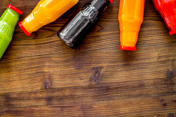 bottles with fresh carrot, tomato, apple, cucumber, lemon, pomegranate juices on wooden background top view copyspace