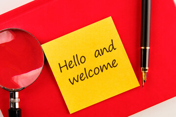 Hello and welcome text on a yellow sticker on a red notebook