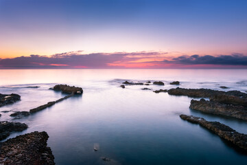 Fototapeta na wymiar Sunrise on the beach of Les Rotes with rocks in the background. Denia. Valencia. Spain
