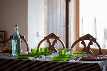 table set up and ready to eat, rustic space with brown checkered cloth tablecloth, green glass...