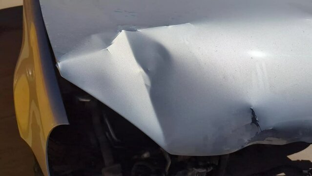 A dented car hood, missing headlights, and bumper after a car accident.
