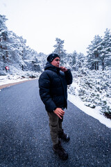 Fototapeta na wymiar Snowy scene, young man in black coat and hat gazes at falling snowflakes.