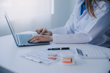 Dentists are discussing dental problems at report x-ray image on laptop screen to patients.