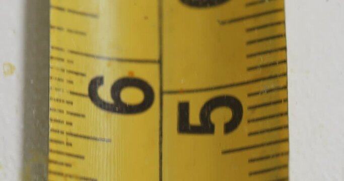 Long yellow centimeter tape line stretching on white table

