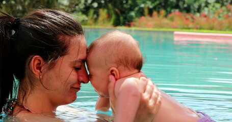 Mother and baby interaction at the swimming pool water showing love and affection smiling