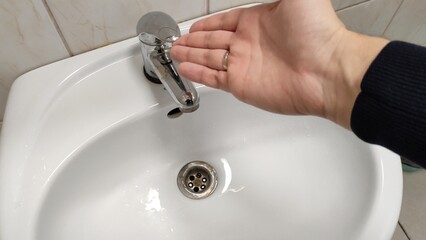 Man opens the faucet in the bathroom