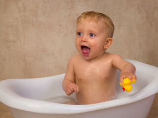 Cute blonde baby boy with rubber duck - 779849036