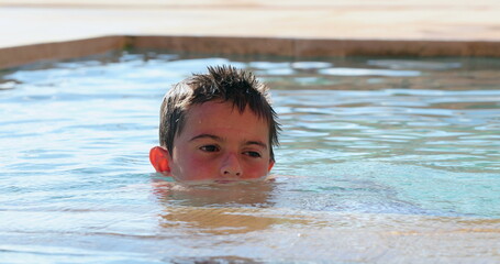Small child boy inside swimming pool water candid contemplative