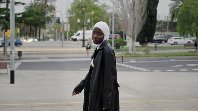 Young modern muslim woman wearing hijab headscarf walking in the city - Smiling Generation Z African Girl