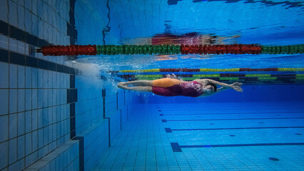 Female swimmer in the water immersion phase, sliding below the water surface, underwater shot....