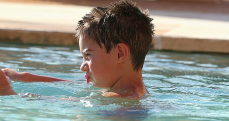 Small child boy inside swimming pool water playing by himself