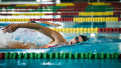 Professional sportswoman, a swimmer during freestyle swimming training, ultimate sports drills in...