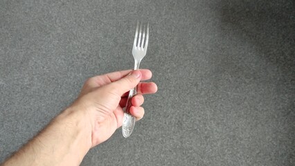 Man holding a metal fork in left hand