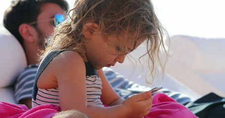 Small girl holding and looking at smartphone device outdoors