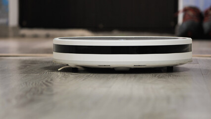 A close-up of a robot vacuum cleaner as it navigates a wooden floor, representing the convenience of modern automated home cleaning technology.