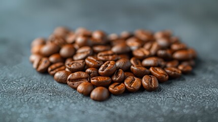   A mound of roasted coffee beans atop a gray surface, adjacent to an unpeeled coffee beans pile