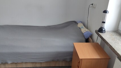Bed in a small cozy student room in a student dormitory