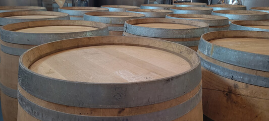 Fototapeta premium Wooden barrels with stacked wine stored in cellar with oak color