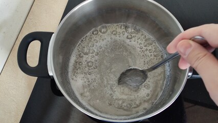 Sugar dissolves in a saucepan on the stove. Making homemade paste for sugaring.