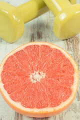 Ripe grapefruit and dumbbells for fitness. Fruits as source minerals and vitamins