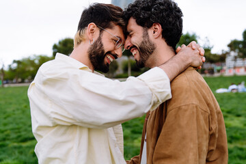 Happy bearded gay couple hugging in park