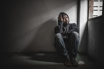 Asian man addict drug in the deserted place,A junkie feels alone in this world,Sad young man sitting in the corner of the room,People are stressed and have depression
