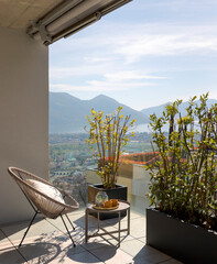 Large terrace of a house in Switzerland with a view of Lake Maggiore. Sunny day and a cosy armchair with cushion. - 779879005
