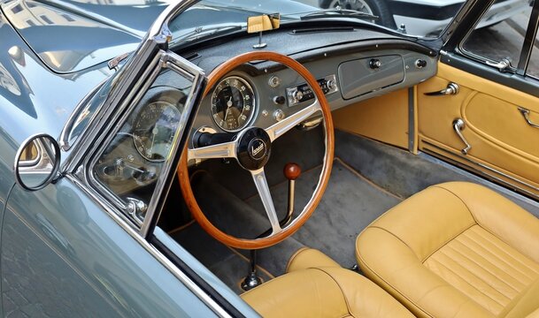 Udine, Italy. April, 8 2024.  Wooden steering wheel,  dash and brown leather interior of Lancia Aurelia, luxury convertible car  from Fifties, during a vintage car gathering.