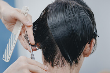 Naklejka premium Concept Barbershop for man. Closeup master hairdresser does hairstyle and style with scissors and comb