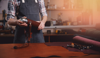 Tailor man hold product from natural leather brown color on workshop background