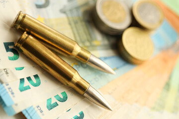 Yellow cartridges and shell casings on euro banknotes. Lot of bills of European union currency and ammo close up