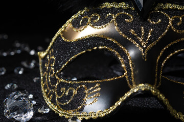 Close-up view of Masquerade gold mask with gemstones on black background.