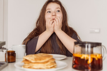 Pre-teen Girl looks at a stack of pancakes with the desire to eat them. High quality photo
