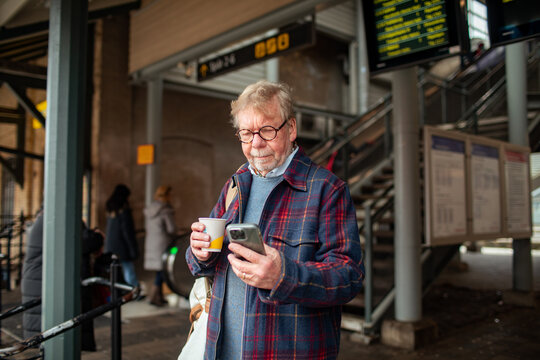 Senior man at the train station using smartphone