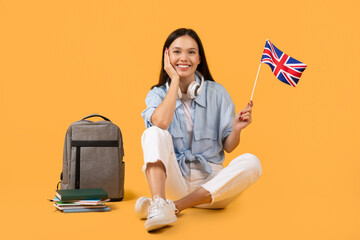 Woman with headphones holding UK flag on yellow background