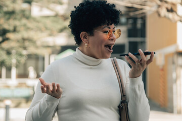 black woman sending an audio or voice message with phone on the street