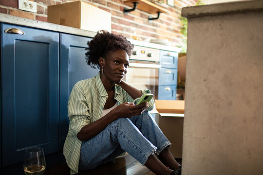 Woman using smartphone on floor with moving boxes around