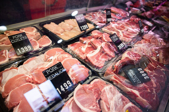 looking into a butcher shop cabinet with pork and steak products