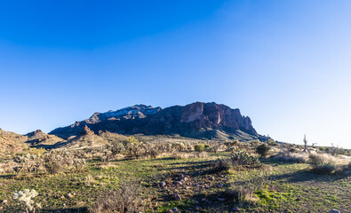Daytime panorama photo of the Superstition Mountains in Arizona with a light dusting of snow and clear blue sky.