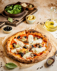 Yummy tabletop pizza with olives, spinach and olive oil
